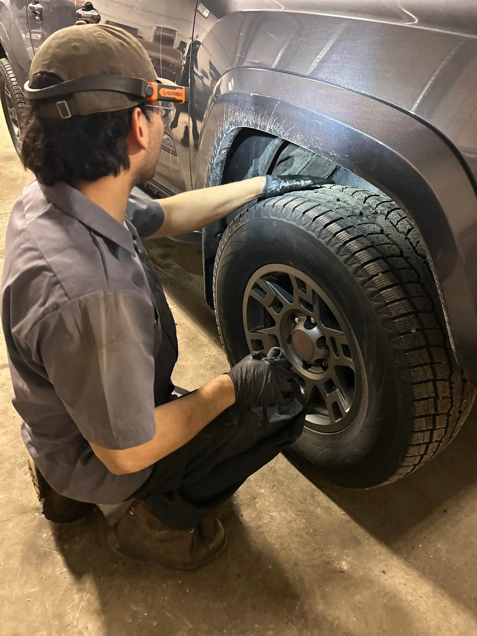 Technician standing beside a car tire performing inspection