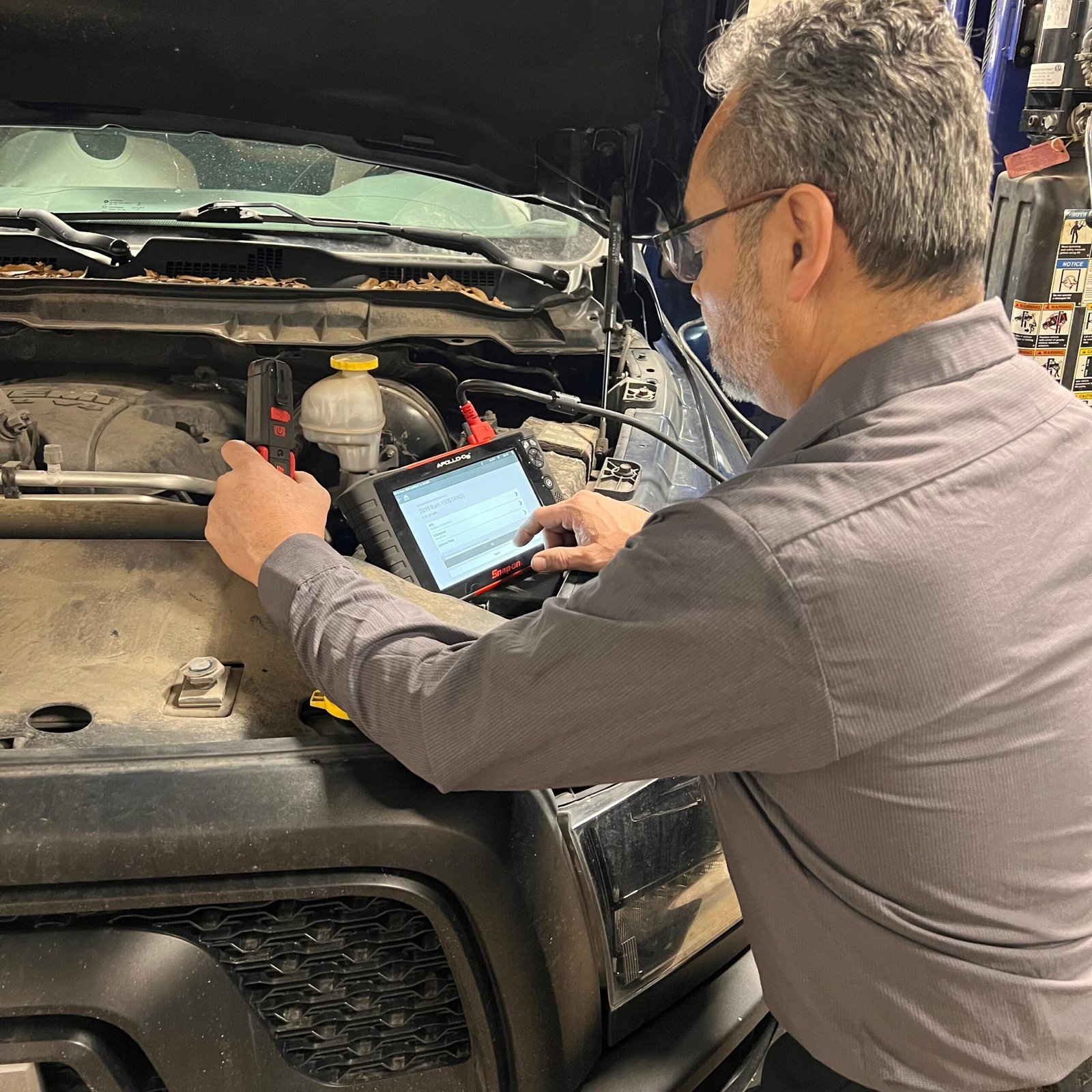 Owner using a tablet connected to a car for engine diagnostics
